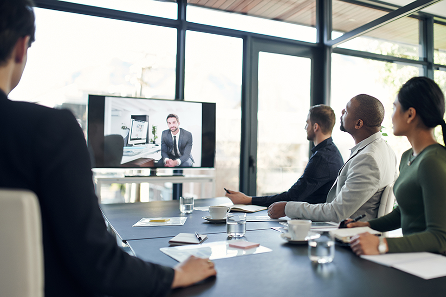 Image of staff in a meeting and online.